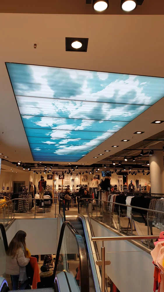 Illuminated ceiling with a sky image above the escalator